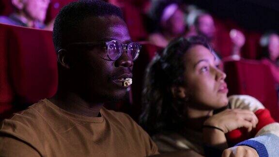 一个女孩和她的非裔美国朋友在电影院看一部严肃的电影