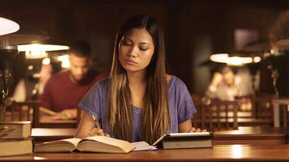 一个亚洲女人晚上在图书馆学习