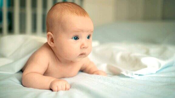 可爱的婴儿美丽的蓝眼睛躺在白色的床上