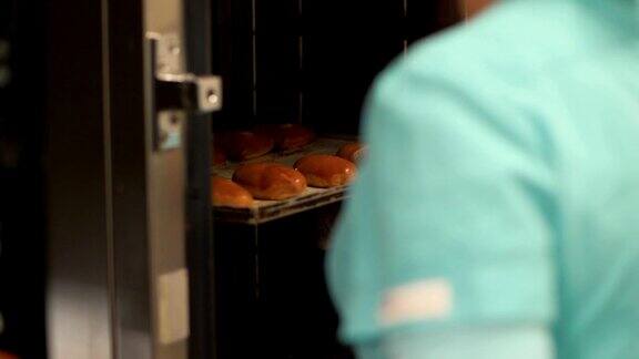 面包师打开烤箱在餐厅厨房端上装有烤肉饼的托盘