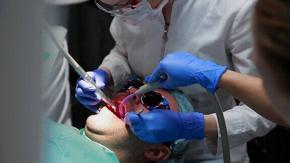 牙医和护士正在给一个病人补牙用bormashenko钻牙清除蛀牙和密封