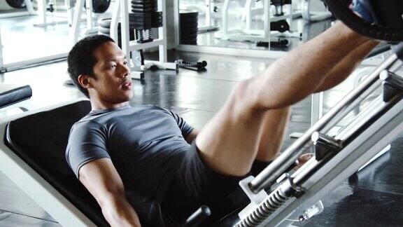 帅哥在健身房的机器上锻炼他的双腿