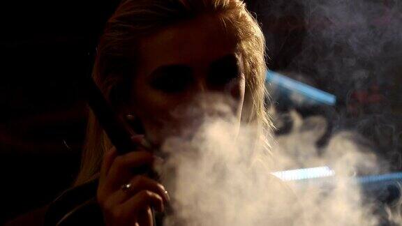 一个女孩抽着雪茄的特写镜头她对着镜头吐出很多烟雾