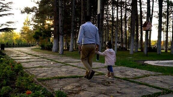 年轻的父亲和女儿在城市公园散步