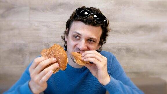 一名男子坐在咖啡馆里一边吃汉堡一边吃沙瓦玛三明治