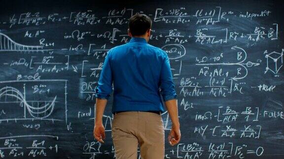 聪明的年轻数学家接近黑板并完成解决长和复杂的方程