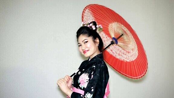 美丽的艺妓穿着传统的日本和服和扭曲的红色阳伞