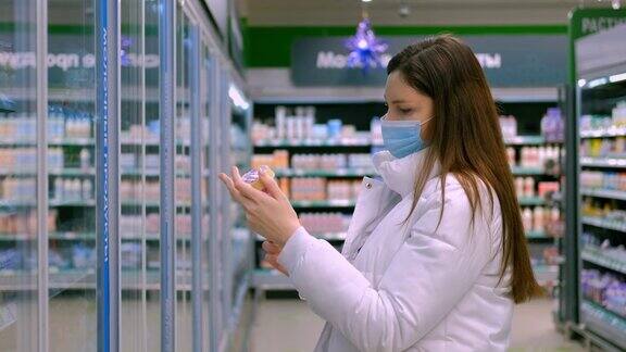 一位戴着医用口罩的妇女走到商店的冰箱前拿出食物