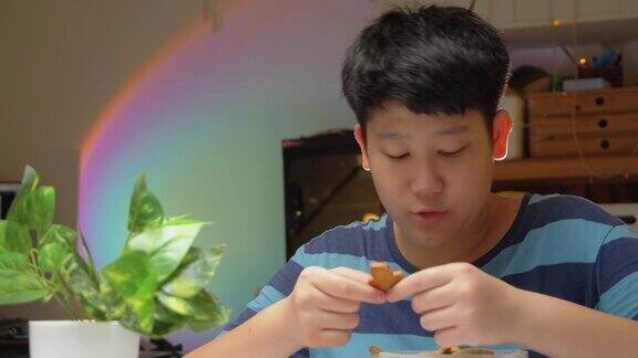 亚洲男孩晚上在家吃饼干万圣节概念