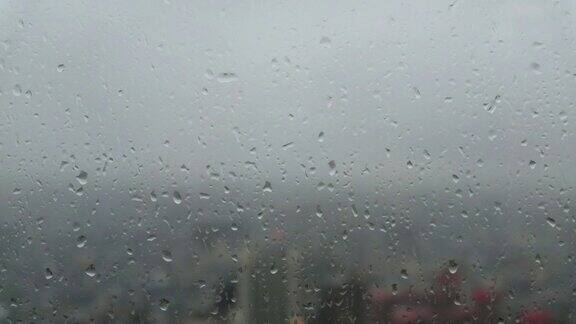透过玻璃窗外的城市景观与雨滴在摩天大楼