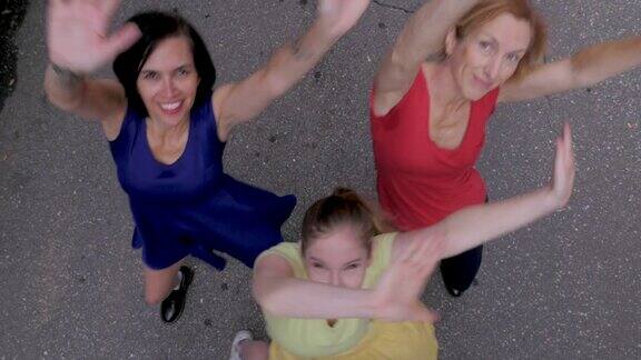 三个漂亮的女人看着镜头挥舞着她们的手臂跳舞