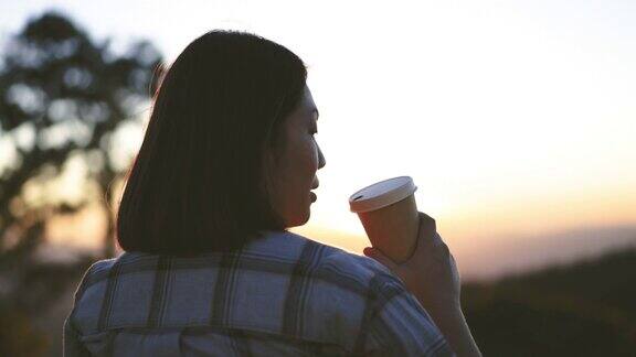 女人在户外放松与咖啡杯在山上的日落时间