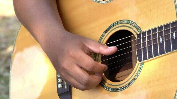 4K视频选择聚焦近距离拍摄的年轻男子手弹奏铜管琴弦的原声吉他年轻音乐家的手在吉他上弹奏和弦