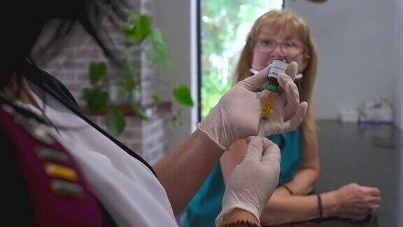 护士为一名老年妇女准备COVID-19疫苗注射