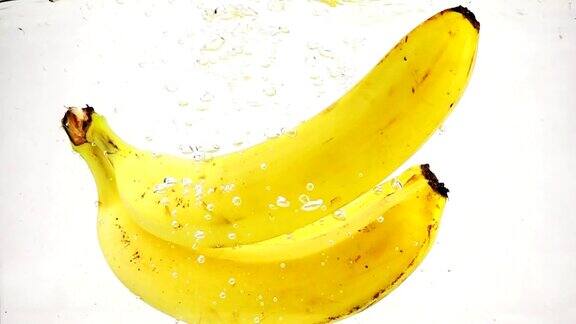 香蕉带着很多小泡泡掉进水里视频香蕉在孤立的白色背景