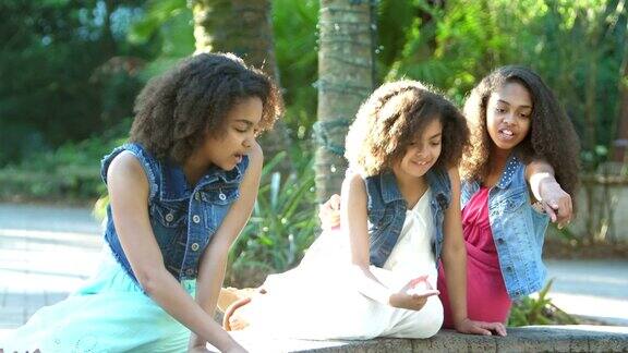 三个非裔美国姐妹在公园聊天指指点点