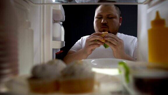 胖子在冰箱前嚼汉堡吃垃圾食品上瘾肥胖