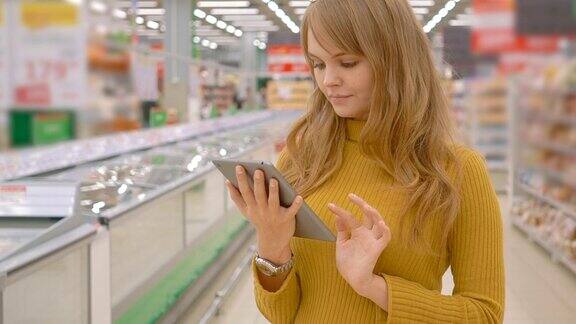 女人在超市购物在平板电脑上使用手机应用程序