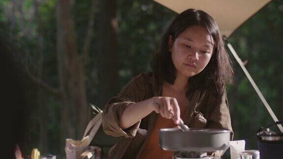 野营时用平底锅煮早餐的年轻女子