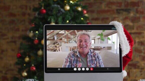 年长的白人男子在电脑上与圣诞装饰和圣诞树视频通话