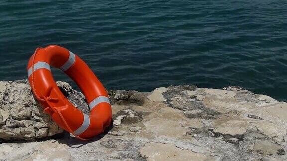 一个红色的救援浮标靠在一块石头上背景是水流