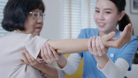 年轻的亚洲老年公民女性与搓洗护士物理治疗工作者在家里为年老的父母康复治疗服务按摩对老年人的护理对老年人疼痛关节的锻炼