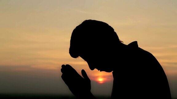 在日落时祈祷的年轻人