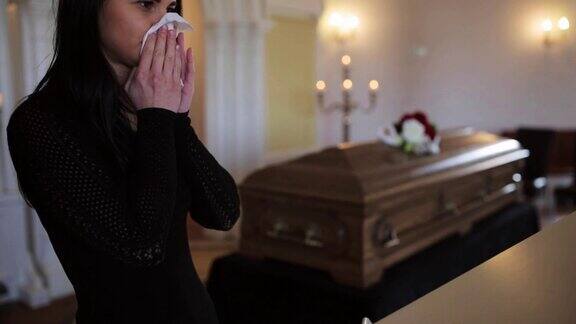 在教堂举行的葬礼上拿着抹布和棺材的女人