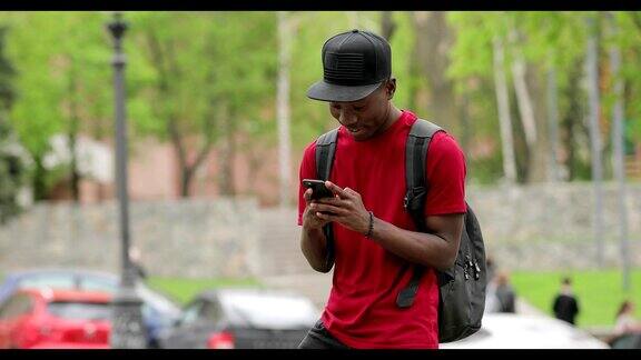 一名身穿红色t恤的非裔美国男子用智能手机上的应用程序大笑