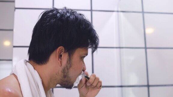 年轻的亚洲男人在浴室里刷牙侧视图