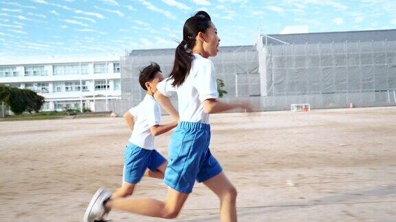 小学的男孩和女孩在学校操场上跑步