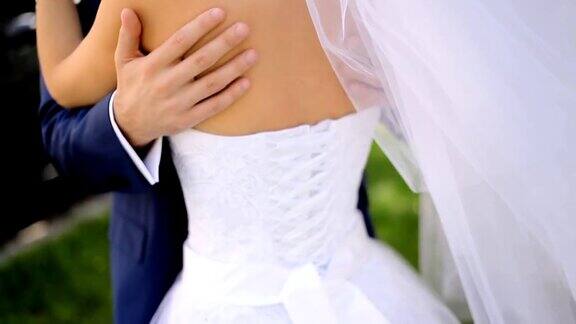 身穿蓝色西装的新郎温柔地抚摸着身穿白色复古礼服的新娘的后背