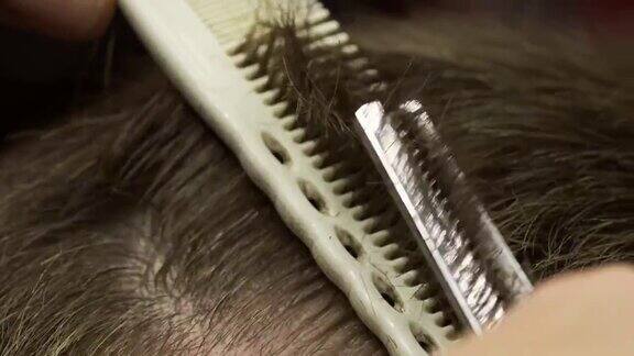 一个理发师用梳子和剪刀剪一个男人的头发的特写