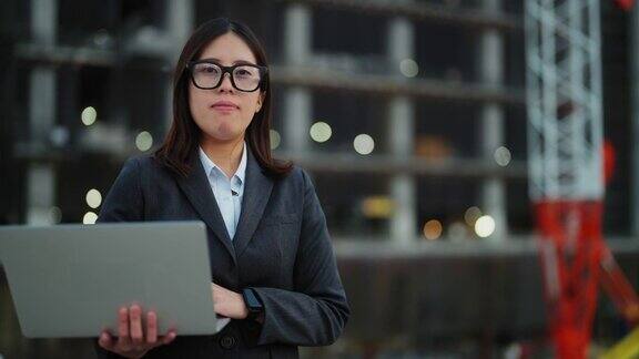 戴着智能眼镜在施工现场使用笔记本电脑的年轻女工程师的照片