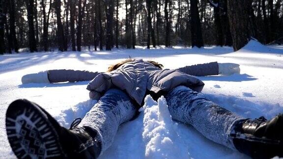 穿着冬衣的少女躺在白雪覆盖的草地上像天使一样快乐的女人在雪地里玩享受冬天的时光快乐的女士在户外玩寒假慢镜头