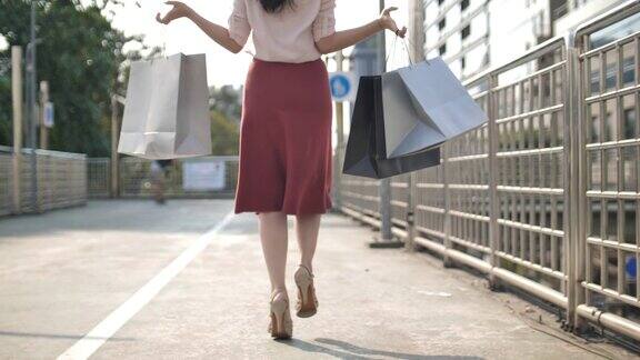 慢动作亚洲女人跳快乐购物袋购物