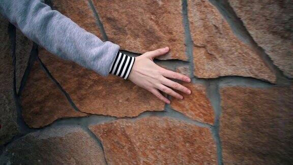 女性的手触摸一堵灰泥墙