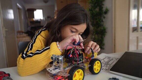 一个聪明的女学生把电缆插到她制造的自动驾驶机器人汽车的主板上