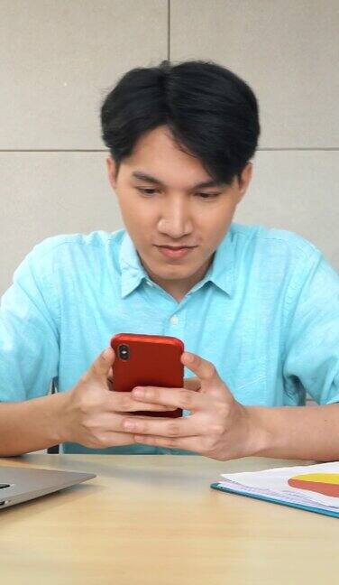 亚洲年轻的商人在办公室用智能手机发短信