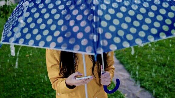 一个穿着雨衣在雨中使用智能手机的女人