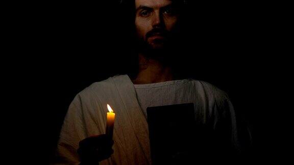 耶稣基督戴荆棘冠冕手持圣经和燃烧的蜡烛先知