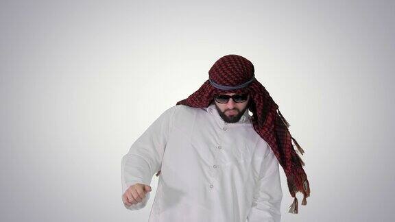 英俊的阿拉伯酋长戴着墨镜在渐变背景上跳一些很酷的舞蹈