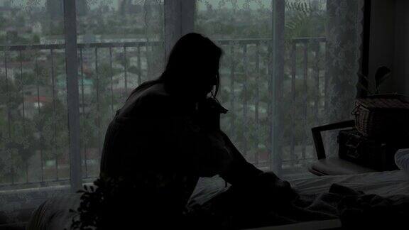 沮丧的年轻美丽的亚洲女人独自坐在公寓卧室的床上哭泣孤独悲伤的女孩想起悲伤烦恼消极情绪与心理健康