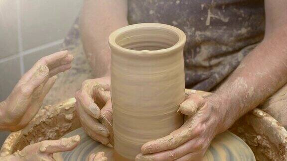 两只手交织在一起在陶工转盘上形成一个陶罐