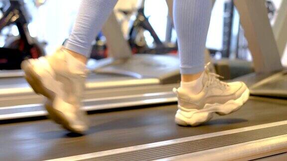 女性穿着运动鞋在跑步机上跑步特写侧视图