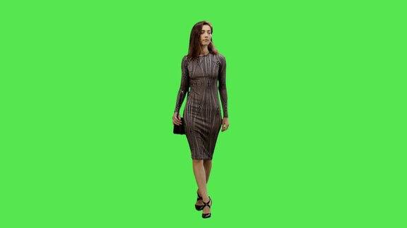 随意年轻的黑发女孩穿着裙子走在一个模型的绿色屏幕在背景