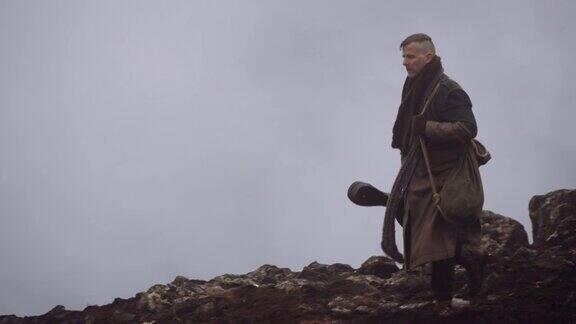 穿大衣的男人走过迷雾和岩石景观