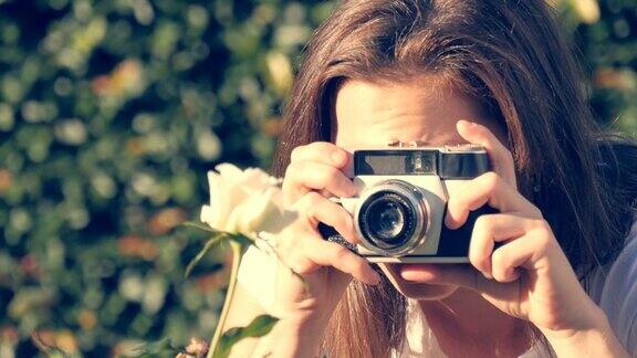 女孩用老式复古相机练习摄影拍下一朵花的照片