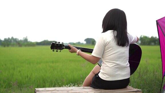 亚洲年轻女子在露营时弹吉他