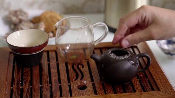 便携式竹桌上的茶道把开水倒进茶壶里冲泡茶叶